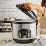 Compact Dash mini rice cooker on kitchen counter with steamed rice and vegetables.