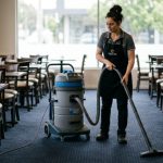 A commercial vacuum cleaner being used on a restaurant dining room floor between service shifts