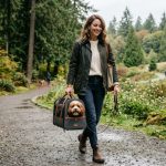 Stylish traveler carrying a sleek premium pet carrier in a Washington park.